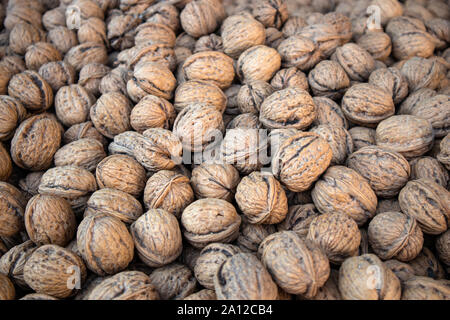 Walnuts background, texture. Dried nuts whole with shell on market display, close up view Stock Photo