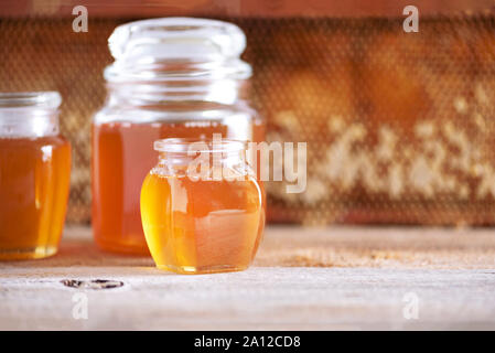 Honey products background. Honeycomb frame, bee pollen granules, honey in glass pot, almond nuts on grey concrete background. Copy space. Autumn harve Stock Photo