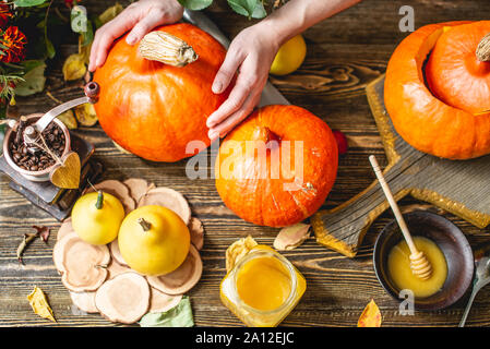 Orange pumpkins for baking with honey and cinnamon on wooden table background. The concept autumn food Stock Photo