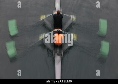 Blurred motion overhead view of a double scull pairs boat, two oarsman in a sculling boat on the water, mid stroke. Stock Photo