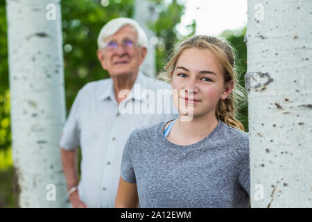 A grandfather and his granddaughter together among trees in a garden. Stock Photo