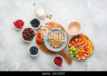 Gluten and grain free paleo granola or muesli made from nuts. Fruit berries platter, strawberries blueberries raspberries peach figs red currant, almond milk, top view, selective focus Stock Photo