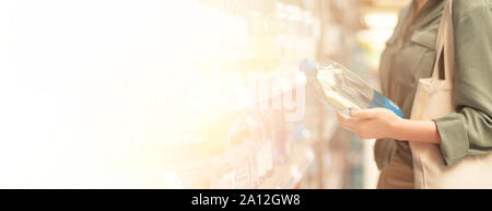 Girl choosing bottle of drinking water in grocery section of supermarket. Copy space. Water balance and body hydration. Healthy diet concept. Sustaina Stock Photo