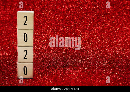 Wooden cubes with numbers 2020 on red sparkling background. Copy space. Festive concept. Stock Photo