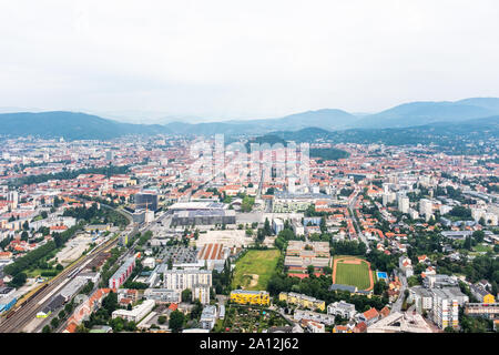 Aerial view of city Graz from helicopter drone with district Jakomini and the east railway station, event-center Messe on a cloudy summer day in Austr Stock Photo