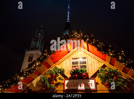 Illuminated Gluhwein (hot mulled wine) stall at Christmas market (Christkindlmarkt) in Central Berlin, Germany, with the Fernsehturm Television Tower Stock Photo