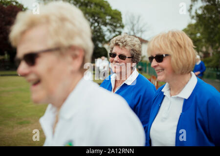 A side view shot of a group of senior women smiling at a bowling green. Stock Photo
