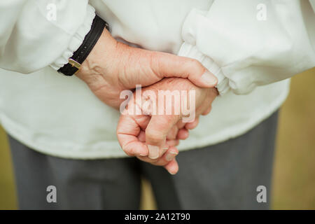 A close up shot of a senior man's hands behind his back, holding them together. Stock Photo