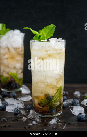 Blueberry Mint Julep Cocktails with Garnish: Two cocktails made with bourbon whiskey, blueberries, and mint leaves over crushed ice Stock Photo