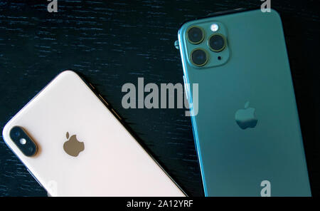 Dubai / UAE - September 21, 2019: New Midnight Green Apple iphone 11 Pro and golden Apple iphone XS on wooden background. Compare iphone products. Stock Photo