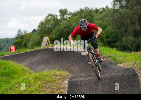 A man rides a mountain bike on a tarmac pump track at Mountain View Bikepark north of Cardiff, Wales. Stock Photo