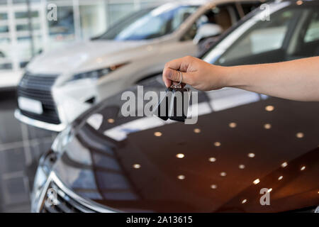 Salesperson holding keys to a new car. Modern and prestigious vehicles. For use as a background. Stock Photo