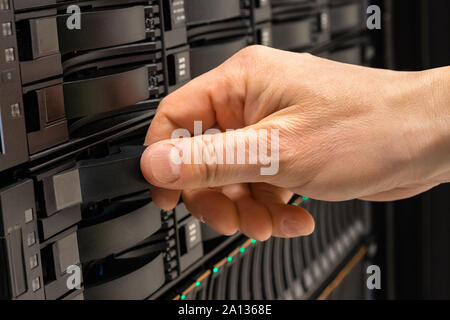 Male IT Professional Replacing Server Drive in SAN Rack Stock Photo