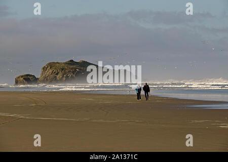 A middle aged couple wander along the empty Pacific Ocean beach in Bandon, Oregon, along the Oregon Pacific Coast. Stock Photo