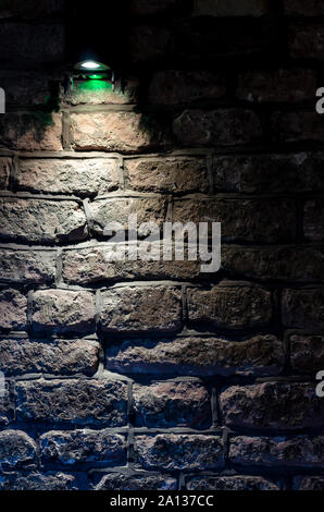 The 16th century wall made of large bricks and a small light source that lights it in the dark. Taken in Chester, United Kingdom. Stock Photo