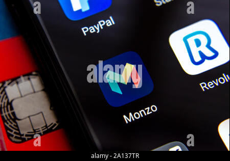 Monzo and Revolut bank apps on the smartphone screen, next to bank card. Stock Photo