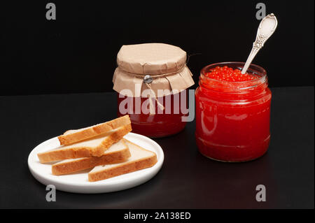 Red caviar in a jar on a black background Stock Photo