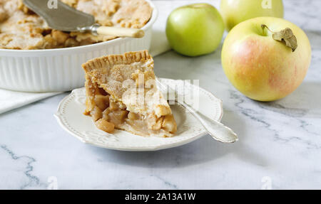A traditional American apple pie decorated with stars and sugar, apples and cinnamon on a light background. Stock Photo