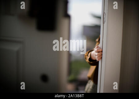 View of a little boy hiding behind a door. Stock Photo