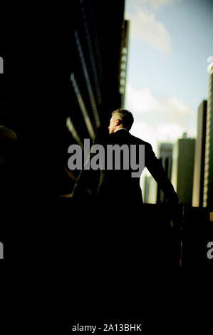Mid-adult businessman leaning on a concrete banister while outside a building. Stock Photo