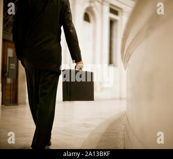 Businessman walking through his office hallway carrying his briefcase. Stock Photo