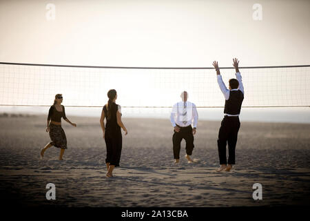 Two couples are playing volleyball on the beach. Stock Photo