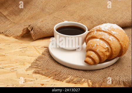 Croissant with a cup of coffee on a plate on a burlap napkin Stock Photo