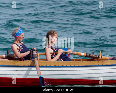 Women rowing in teams of six in traditional hand built pilot gig boats. the annual west country event draws teams from Europe (London Cornish) Stock Photo