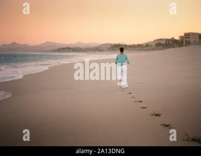 Footprints of a woman are left behind as she walks on the beach. Stock Photo