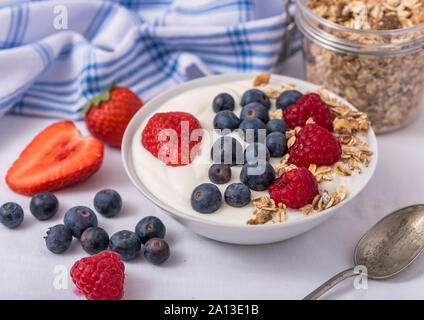 White yogurt in bowl with oatmeal and strawberries, blueberries and raspberries on the top. Stock Photo