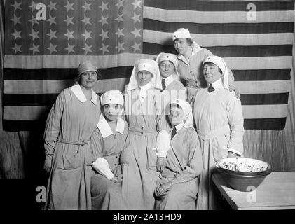 A group of American Red Cross workers standing with The American Flag, Paris, 1919. Stock Photo