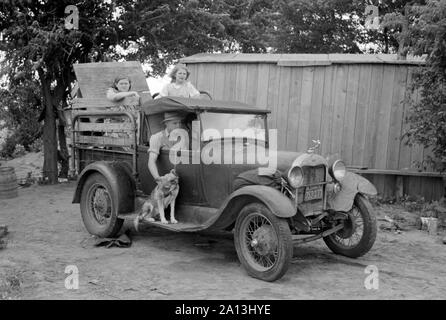 Great Depression era photograph of a migrant family in a packed car preparing to leave. Stock Photo