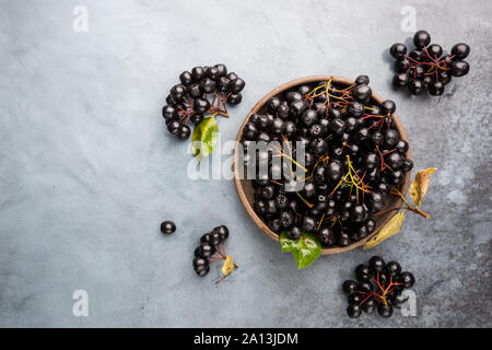 Bowl with freshly picked homegrown aronia berries. Aronia, commonly known as the chokeberry, with leaves, top view Stock Photo