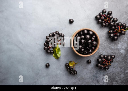 Bowl with freshly picked homegrown aronia berries. Aronia, commonly known as the chokeberry, with leaves, top view
