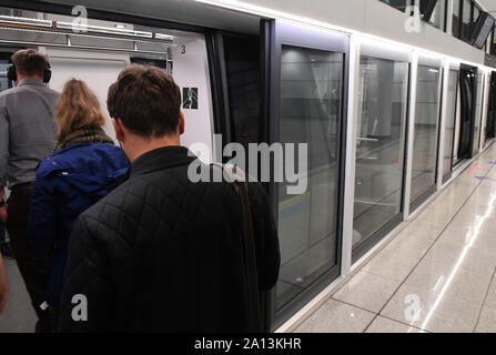 Munich, Germany. 23rd Sep, 2019. Visitors get on a train. The platform that connects the terminals at Munich Airport is secured with a glass wall and extra doors, so that it is not possible to fall into the tracks and fall in front of the train in a crowd. Only when visitors board the train are the doors of the train and the doors on the platform opened. Credit: Felix Hörhager/dpa/Alamy Live News Stock Photo