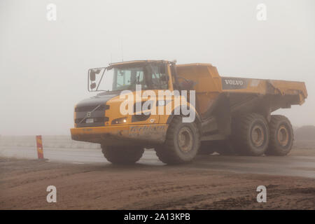 Umea, Sweden - August 23, 2019: work vehicles transport land for new road project in the fog at Roback Stock Photo