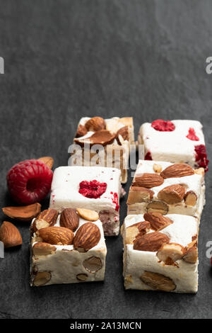 Homemade  nougat bars with almonds and dried fruits on black stone background Stock Photo