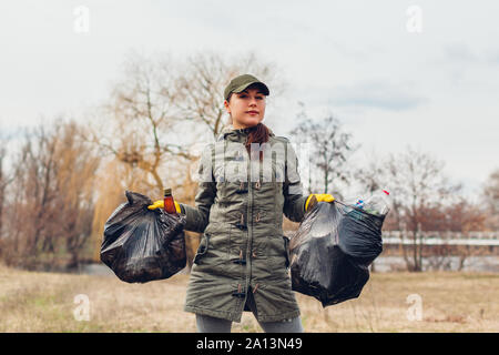 Litter picking. Woman volunteer cleaning up the trash in park. Picking up garbage outdoors. Ecology and environment concept. Saving planet Stock Photo