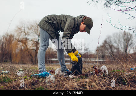 Litter picking. Woman volunteer cleaning up the trash in park. Picking up garbage outdoors. Ecology and environment concept. Saving planet Stock Photo