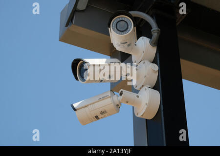 Three outdoor security surveillance cameras mounted together and viewing in separate directions for small airport security monitoring. Stock Photo