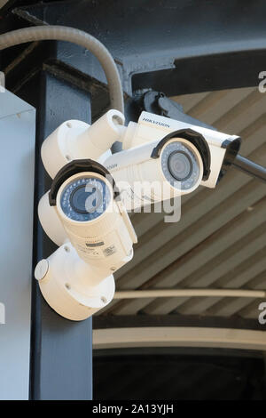 Three outdoor security surveillance cameras mounted together and viewing in separate directions for small airport security monitoring. Stock Photo