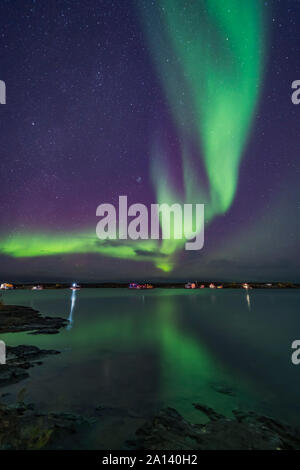 A curtain of aurora sweeps over the houseboats moored on Yellowknife Bay in Canada. Stock Photo