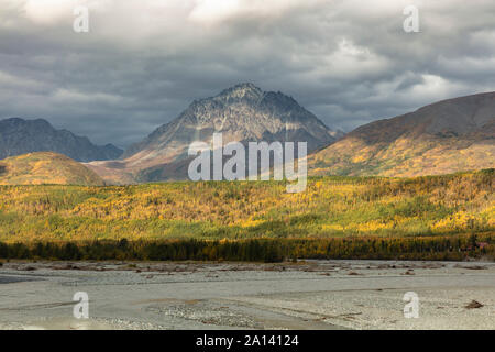 Dramatic storm clouds and sunlight reveal a colorful autumn landscape along the Matanuska River in Southcentral Alaska. Stock Photo