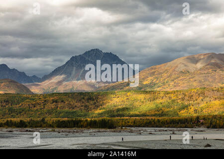 Dramatic storm clouds and sunlight reveal a colorful autumn landscape along the Matanuska River in Southcentral Alaska. Stock Photo