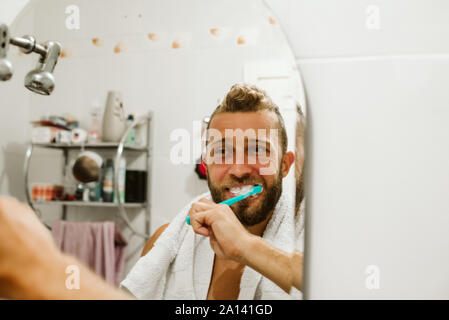 Man with toothbrush cleaning teeth at bathroom Stock Photo