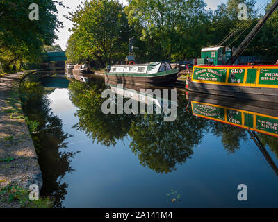 Narrowboats and trees at a boat repair yard reflected in the Ashton Canal, at Ashton-under-Lyne, Tameside, Manchester, UK Stock Photo