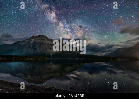 The Milky Way and Vimy Peak are reflected in the calm waters of Middle Waterton Lake, Alberta, Canada. Stock Photo