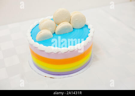Rainbow layered cake with macarons on top on white background Stock Photo