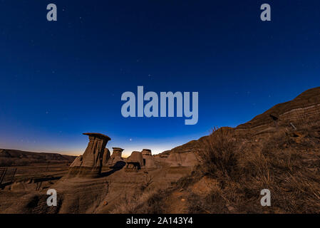 Venus low in the twilight sky above hoodoos in the Red Deer River valley, Alberta, Canada. Stock Photo