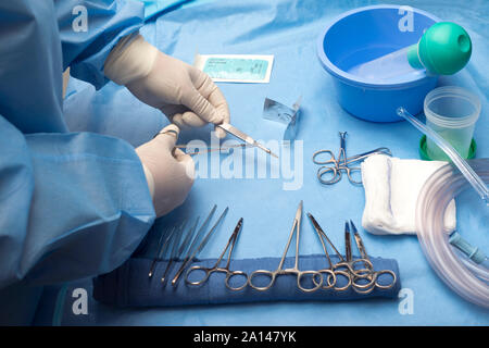 Surgical technician loads scalpel with surgical blade on sterile table. Stock Photo